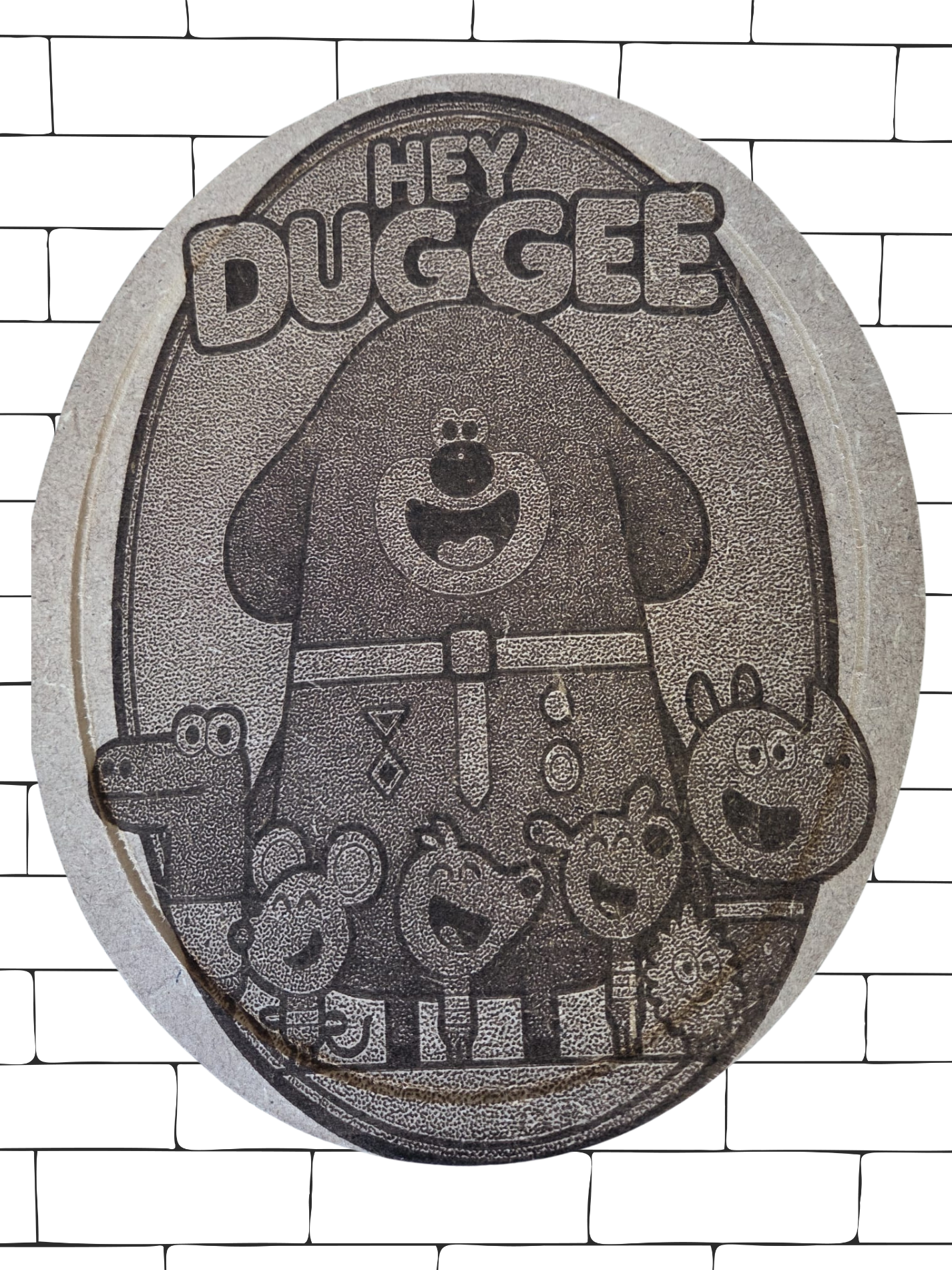 This image shows a circular wooden plaque featuring characters from the children's TV showHey Duggee." The plaque is engraved with detailed line art of Duggee, 