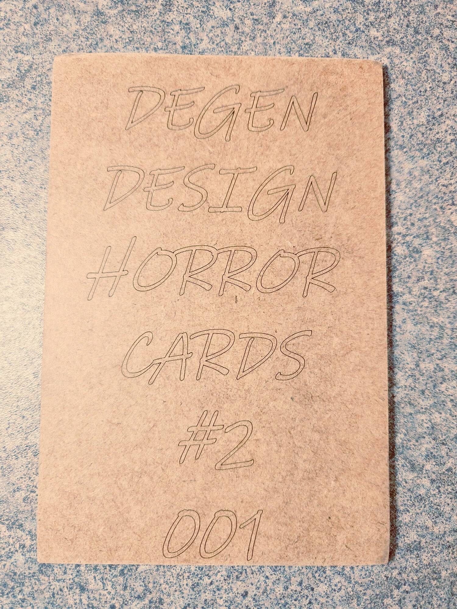 Back of Degen Design Serial Killer Collector Card #2 Ted Bundy with engraved text 'Degen Design Horror Cards #2 001' on textured surface.