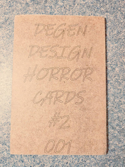Back of Degen Design Serial Killer Collector Card #2 Ted Bundy with engraved text 'Degen Design Horror Cards #2 001' on textured surface.